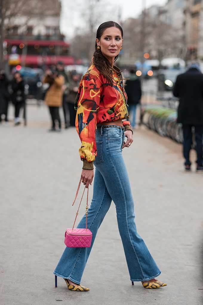 Frau trägt Bomberjacke mit Graffiti-Print, kombiniert mit Bootcut-Jeans