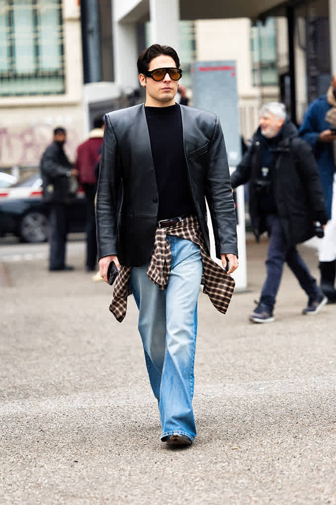 Mann in schwarzer Lederjacke und ausgewaschener Denim-Jeans, mit Karohemd um die Taille