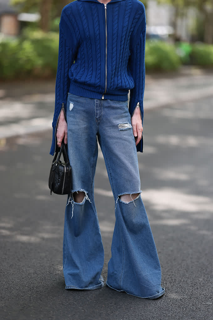 Frau in blauem Strick-Pullover, trägt Destroyed Denim-Jeans dazu