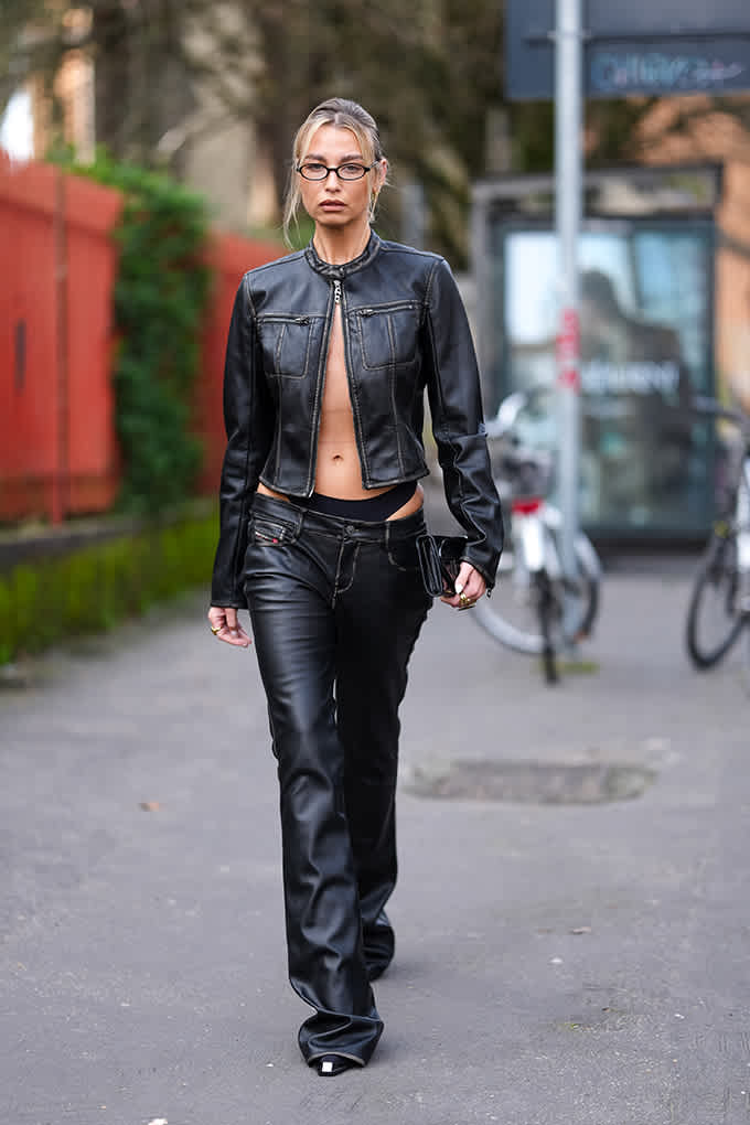 Frau mit kurzen blonden Haaren, trägt knappe Lederjacke in Schwarz mit passender Bootcut-Lederpants