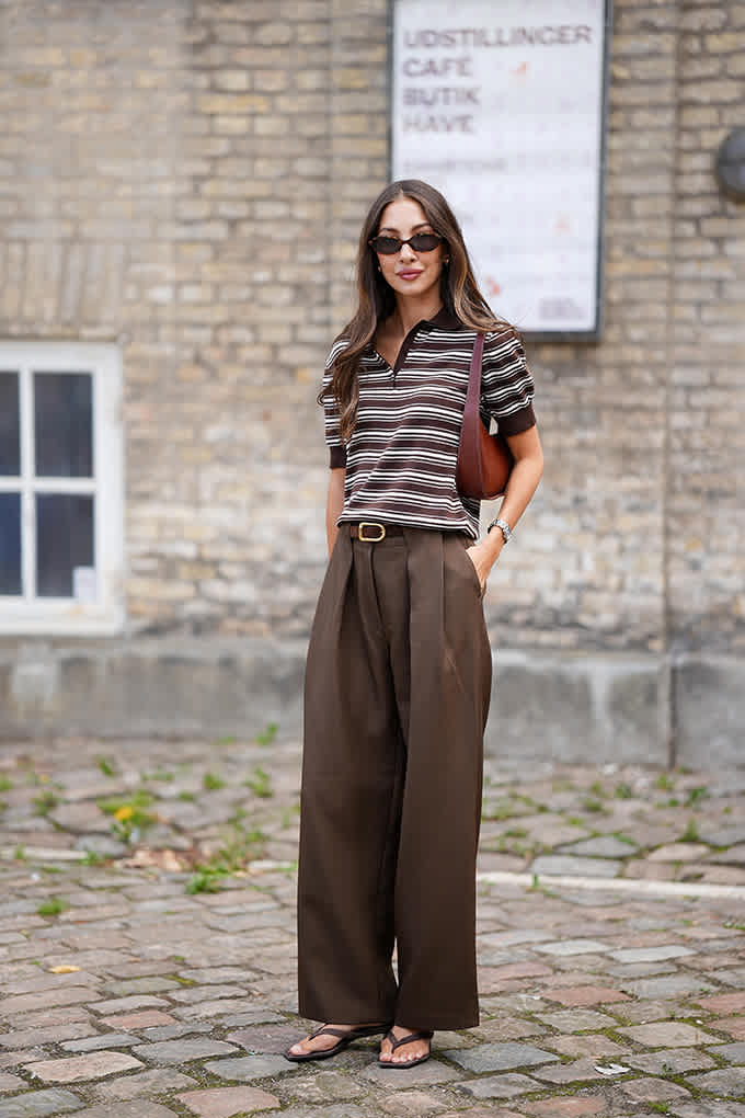 Frau mit Sonnenbrille, trägt Poloshirt und Bundfaltenhose für den Preppy-Streetstyle-Look