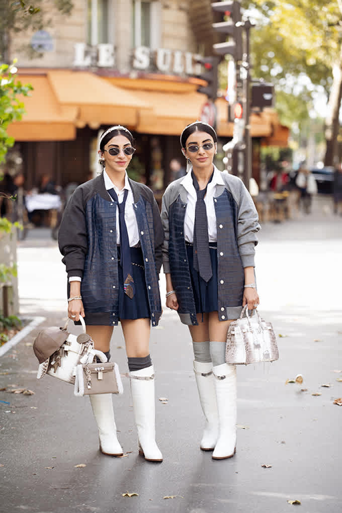Zwei junge Damen in passenden Preppy Outfits, tragen Minirock, Hemd, Krawatte und kniehohe Boots