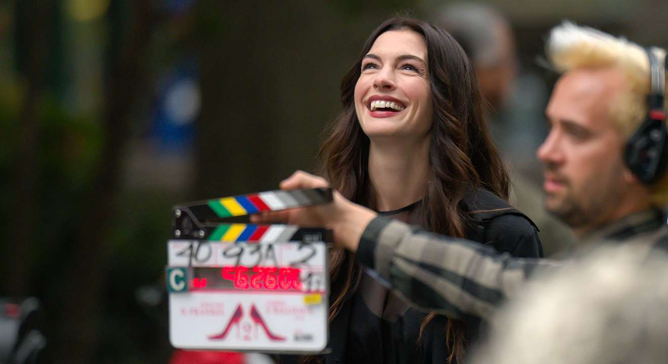Lächelnde Schauspielerin Anne Hathaway steht an Filmset