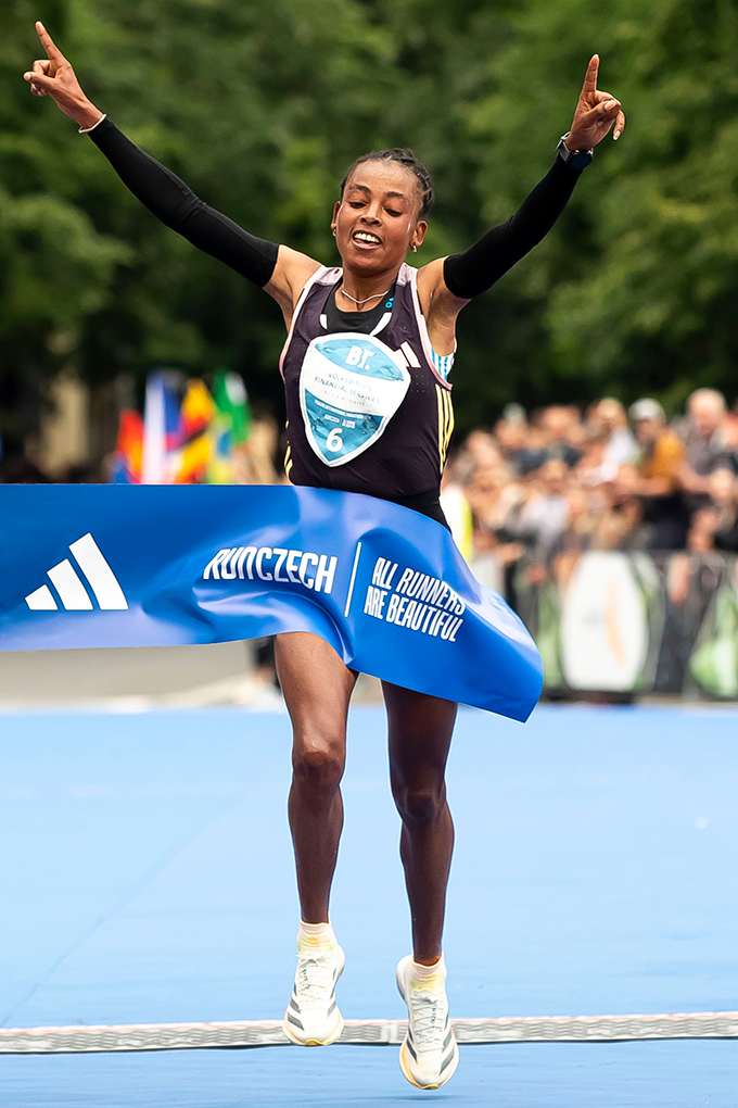 Sportlerin in Adidas-Outfit durchläuft jubelnd eine Ziellinie