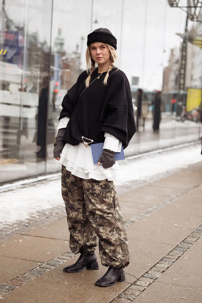 Blonde Frau mit Ponytails, schwarzer Blazer im Layering, mit Camo Pants, auf der Straße