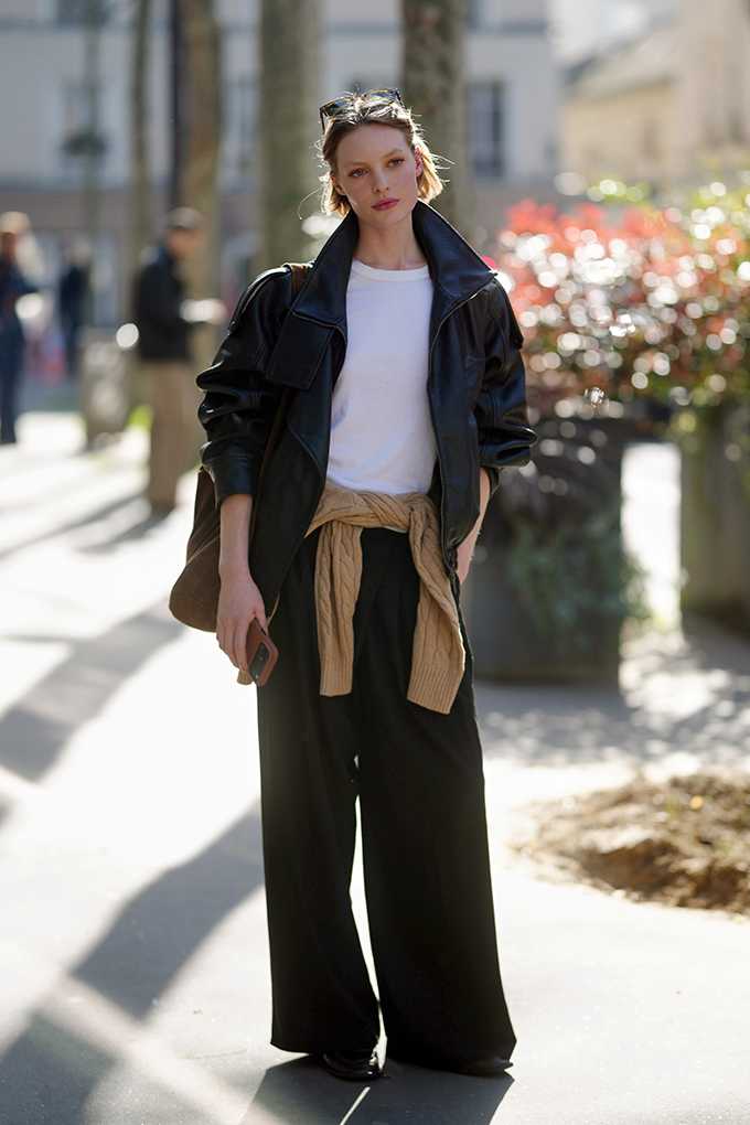 Frau trägt schwarze Lederjacke über weißem Shirt in Stadtkulisse