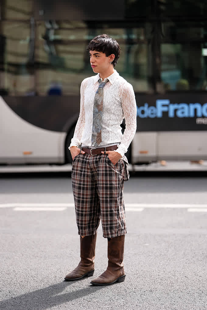 Person in Business-Outfit mit weißem Hemd und Krawatte, Karo-Musterhose und Cowboy-Boots