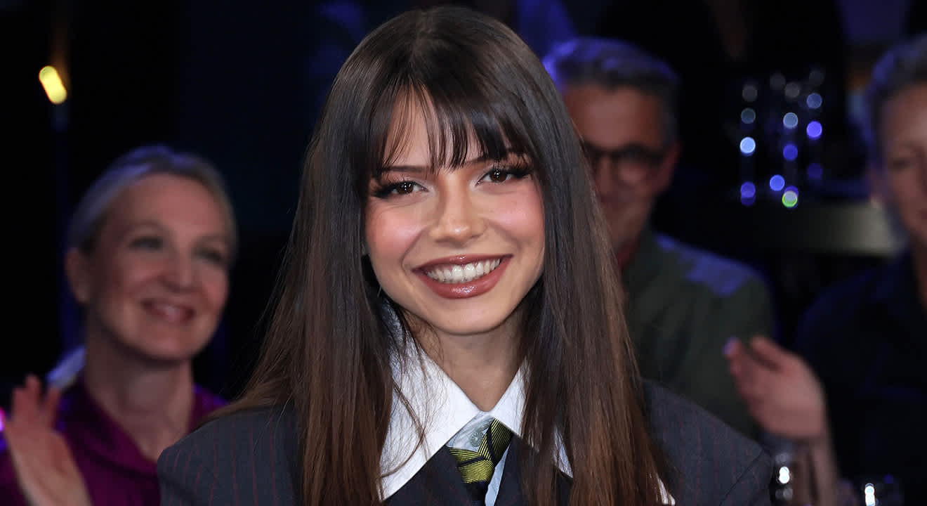 Nina Chuba lächelt Richtung Kamera, trägt dunkelblaues Oberteil mit darunterliegendem weißem Hemd