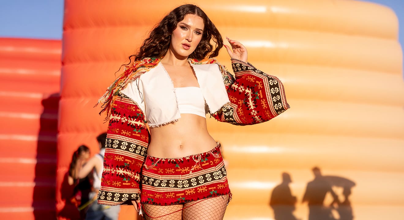 Frau im auffälligen Coachella Outfit bestehend aus einem weißem Crop-Top und einem Set aus Jacke und Rock mit Ethno-Print