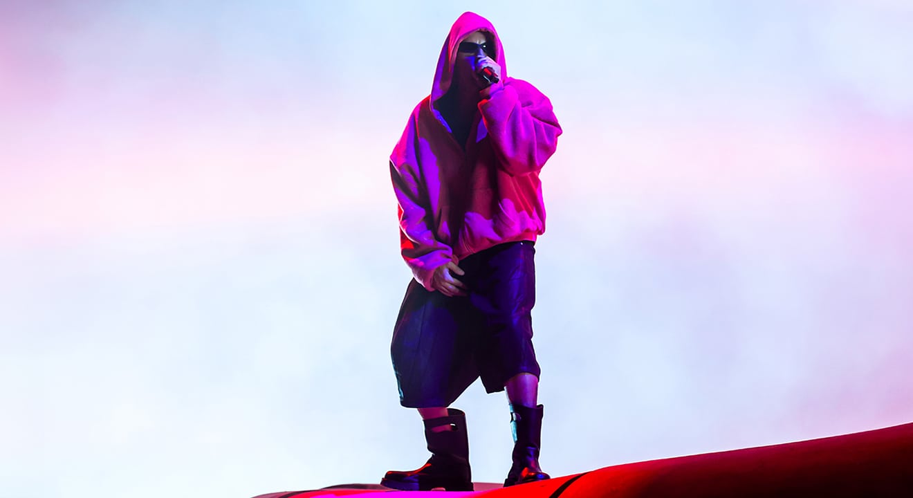 Justin Bieber in einem pinken Oversized-Hoodie, weiten Shorts und schwarzen Stiefeln als Coachella Outfit während seines Auftritts auf der Bühne.