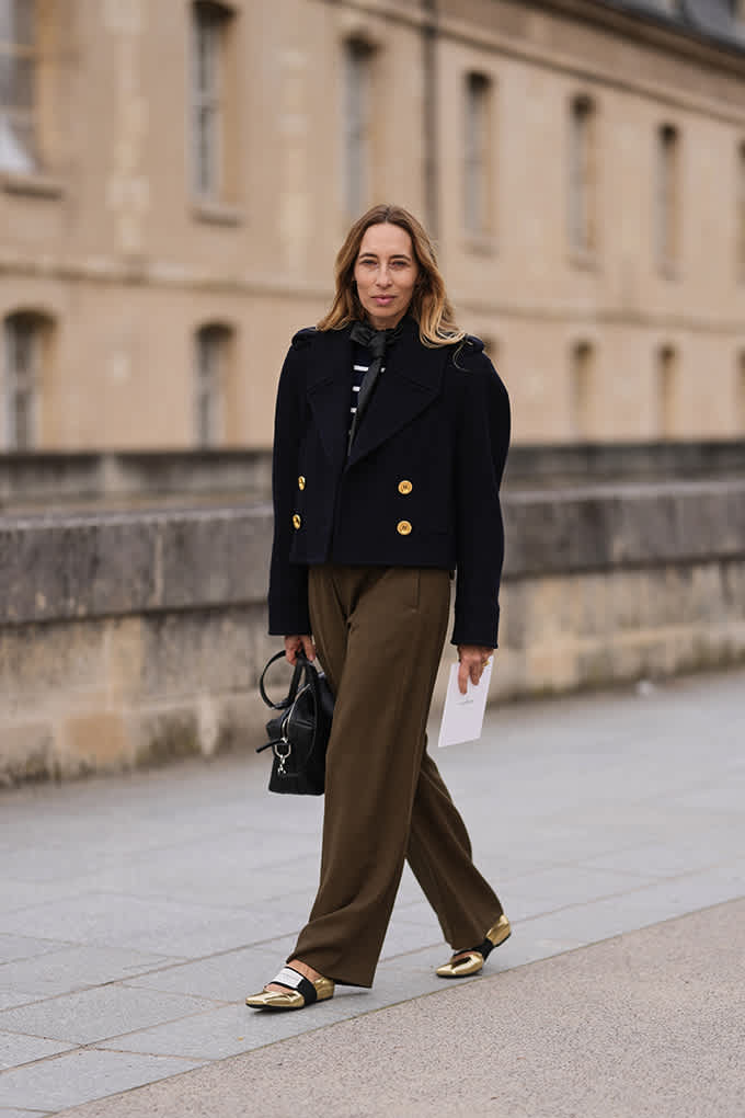 Eine Frau in olivfarbener Hose trägt auffällige goldene Sneakerina.