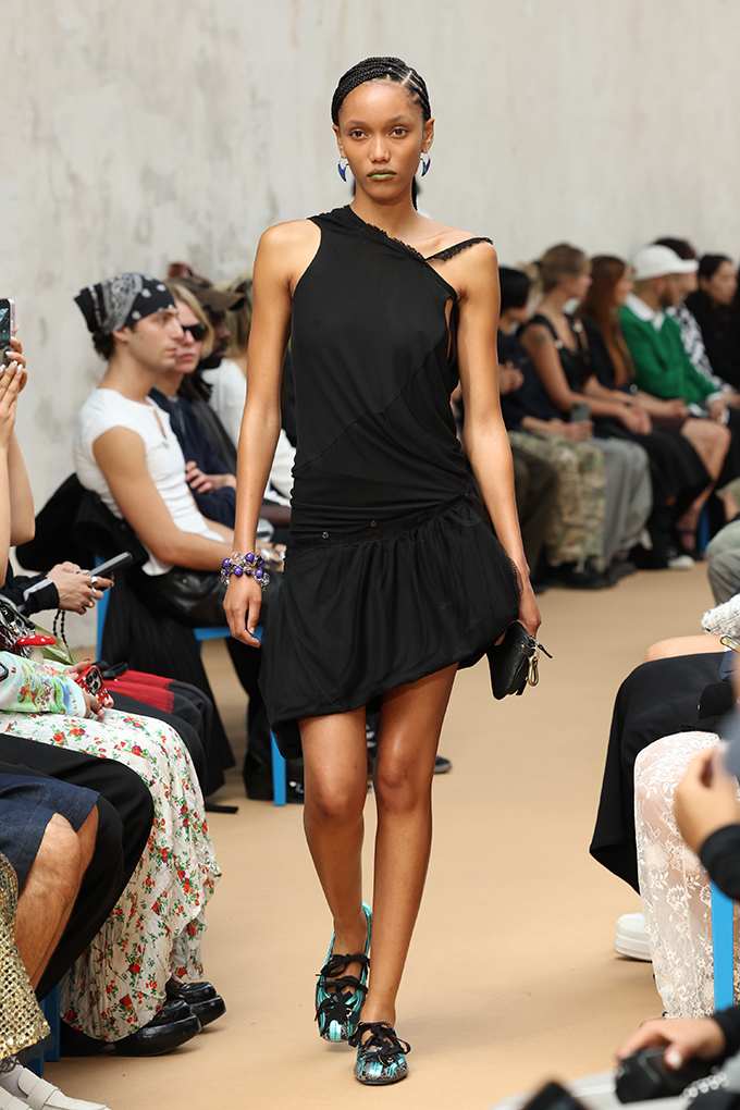 Runway-Model trägt schwarze Sneakerina mit türkisfarbenen Akzenten.