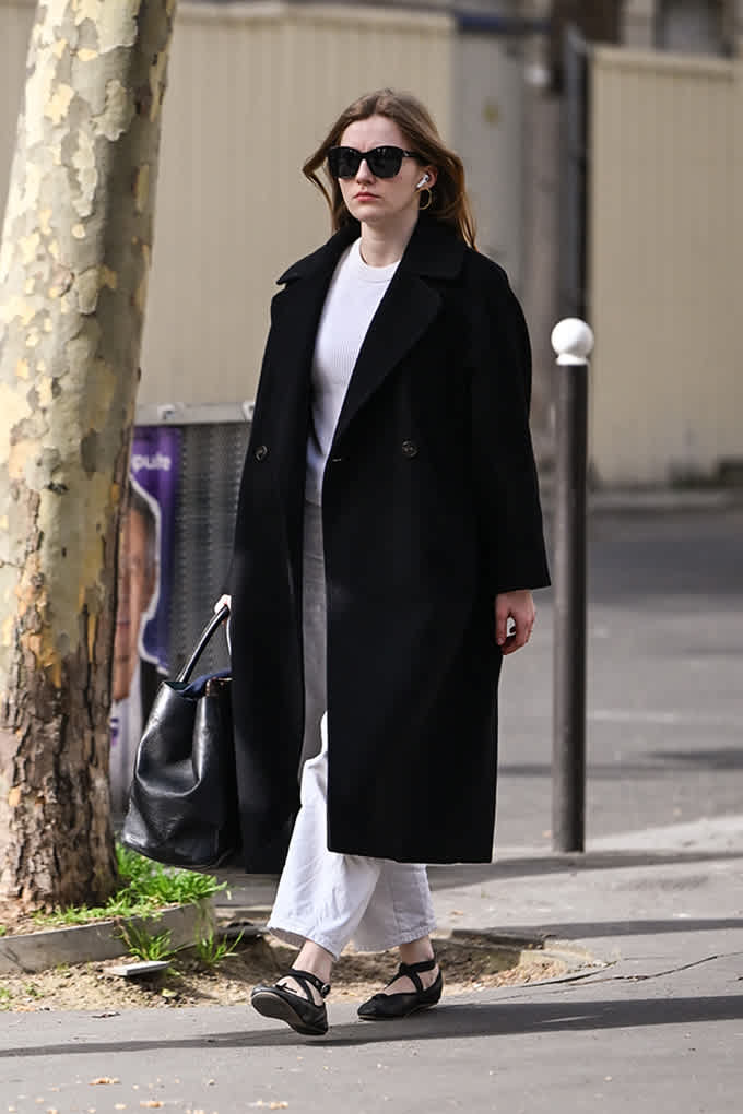 Person trägt Sneakerina-Schuhe zu einem Schwarz-Weiß-Outfit.