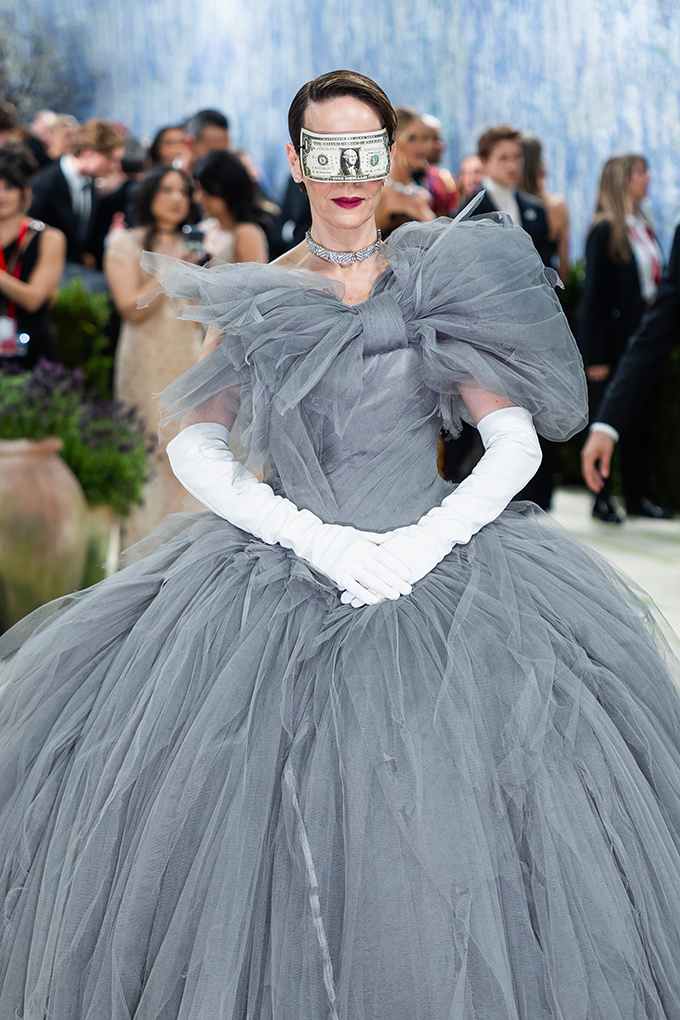 Schauspielerin Sarah Paulson in ausschweifendem grauen Kleid mit weißen Handschuhen und Gesichtsmaske