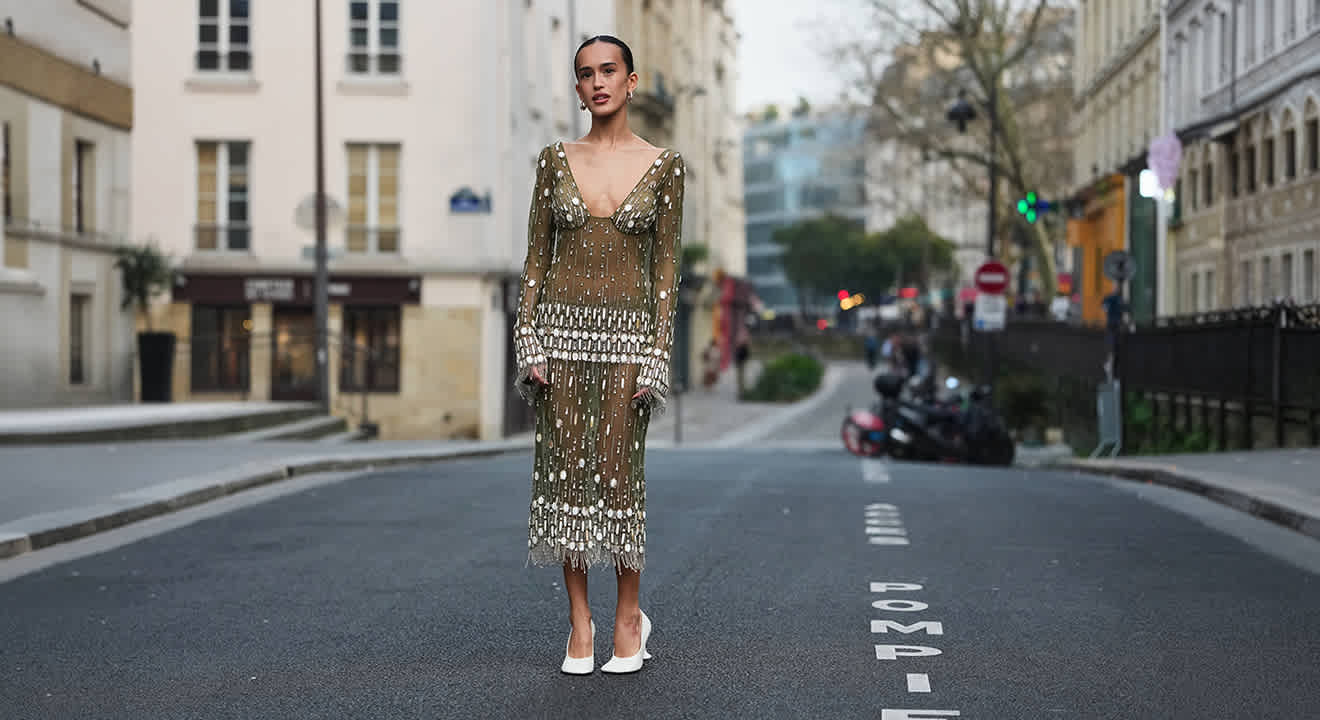 Frau in transparentem Outfit mit weißen Pumps, steht auf Straße