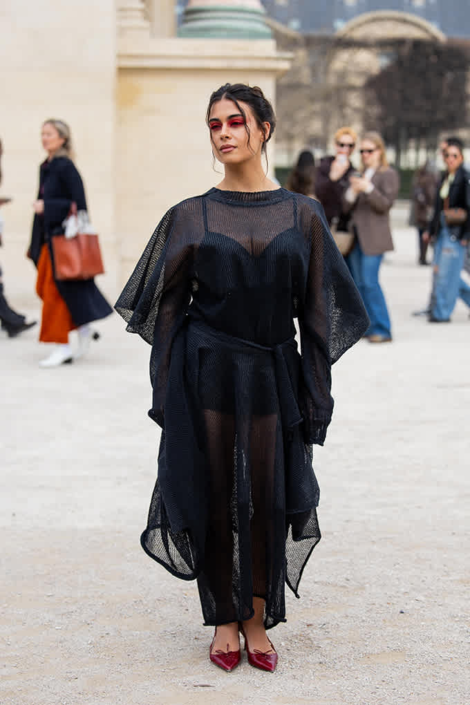 Junge Frau trägt voluminöses Sheer Outfit mit roten Pumps