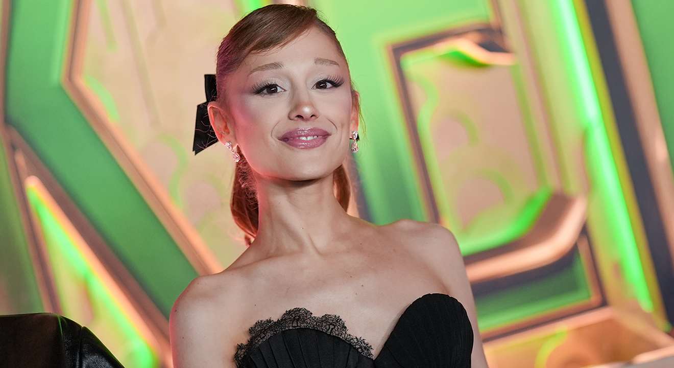 Sängerin Ariana Grande in schwarzem Kleid vor Graffiti-Fassade