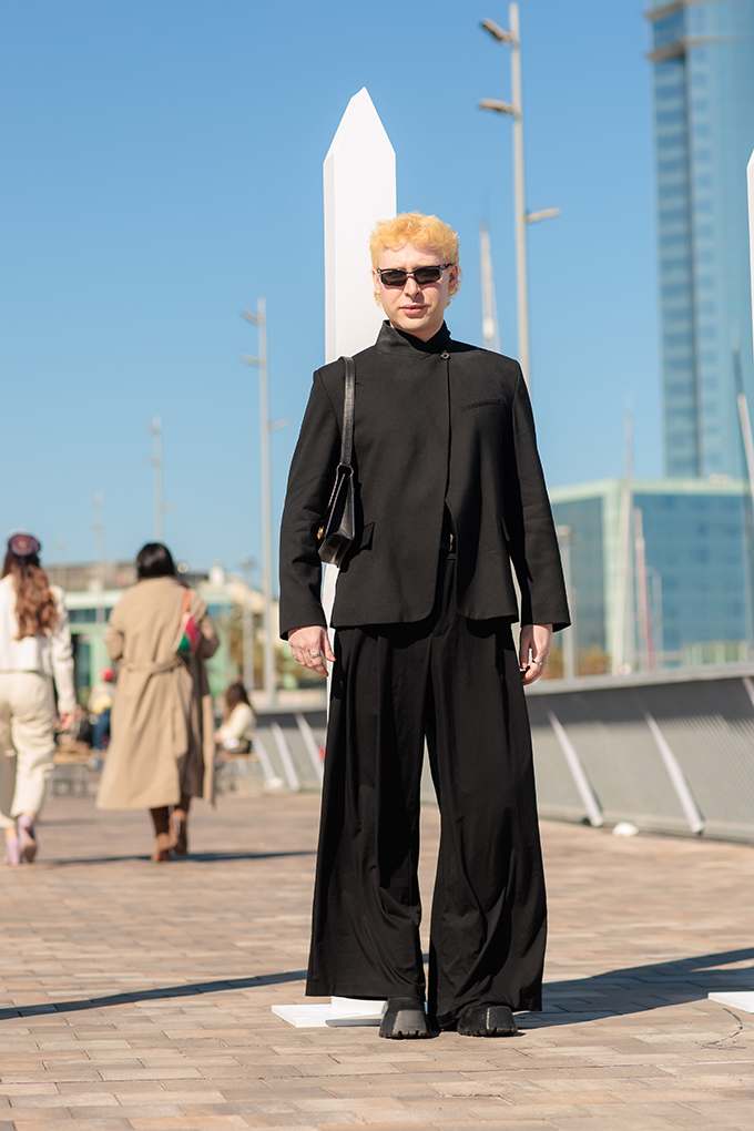 Frau mit blondem Haar-trägt schwarze Kasten-Jacke und passende Wide-Leg-Jeans