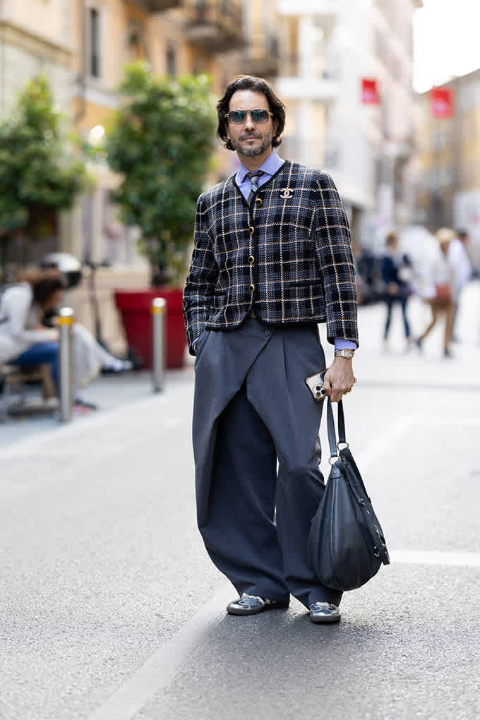 Mann in blauer Tweedjacke und überweiter Hose mit Shopper Bag für den Fluid-Look