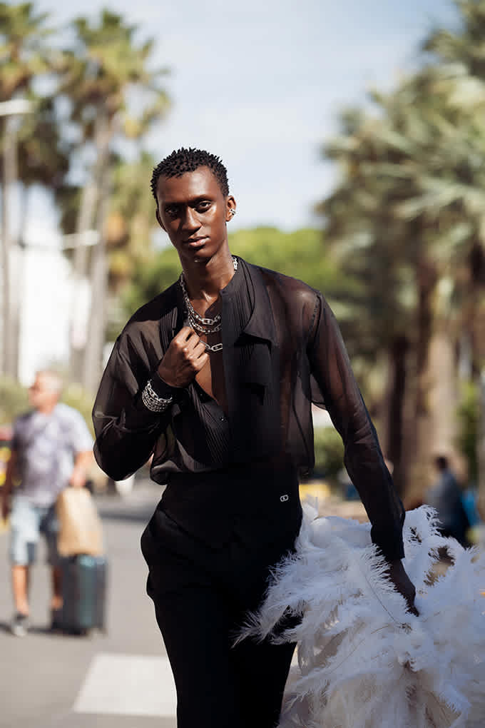 Schwarzes Model mit transparentem Top, trägt weiße Boa in der Hand