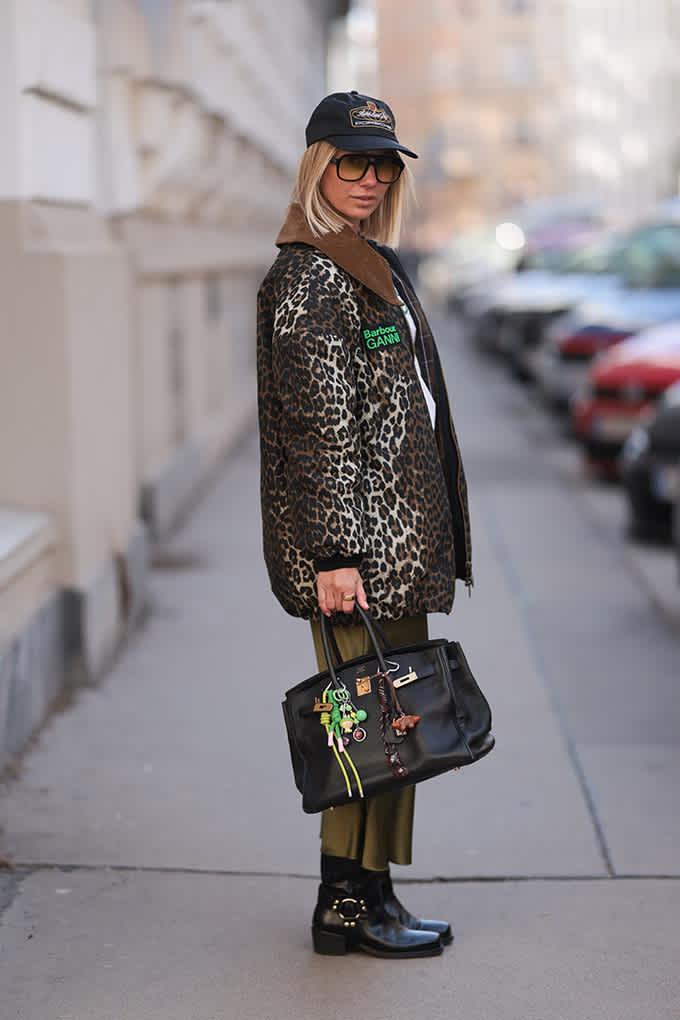 Frau in Bikerboots und Leoprint-Jacke steht auf einem Gehweg