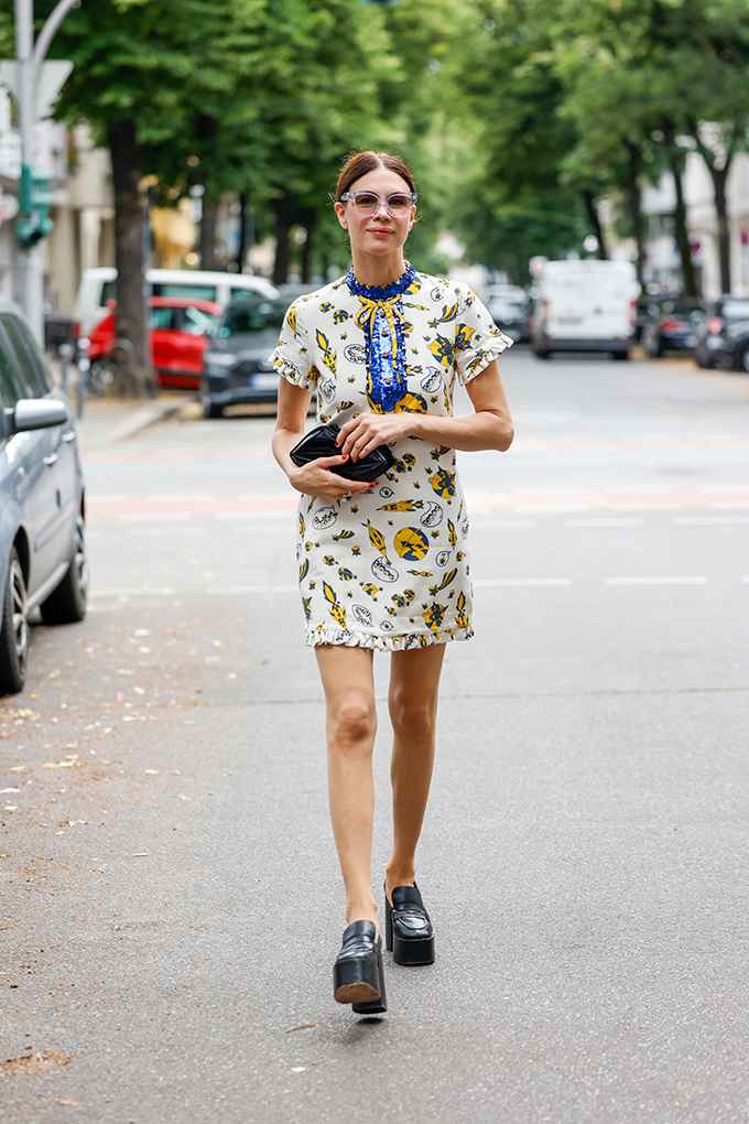 Frau geht auf Straße, trägt kurzes Shiftkleid mit Prints im Retro-Design