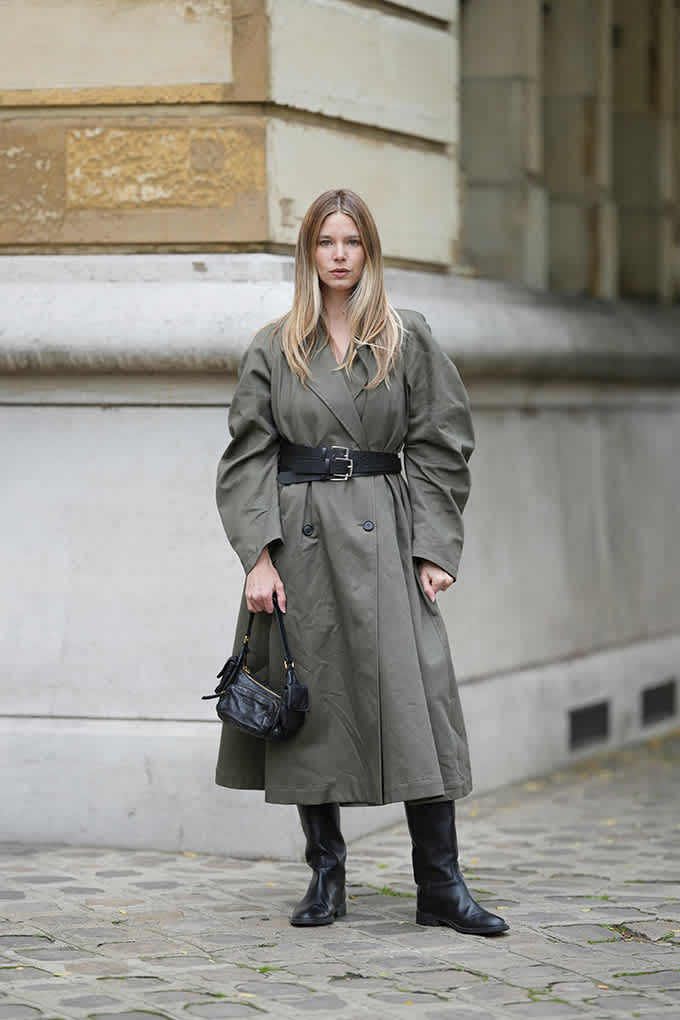 Blonde Frau mit Oversize-Trenchcoat in Grau mit schwarzem Double-Belt um die Taille