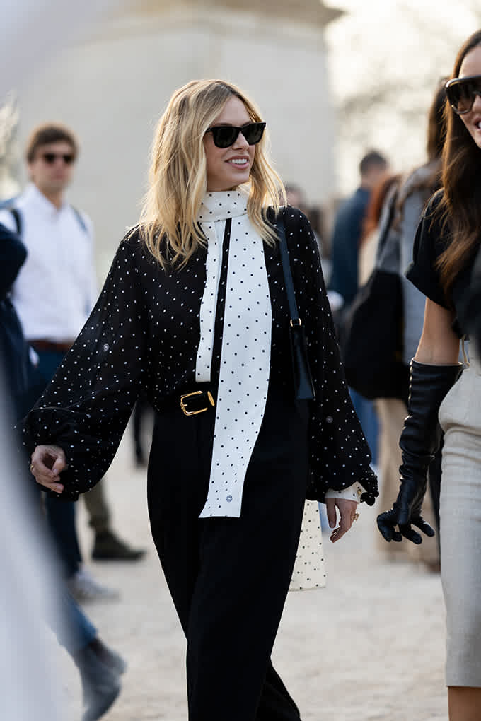 Frau trägt weißes Oberteil mit kleinen Polka Dots und schwarze Jacke mit Polka Dots 
