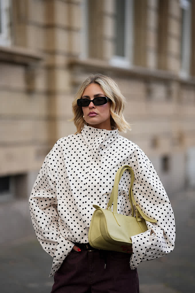 Frau mit gepunktetem Windbreaker und Sonnenbrille
