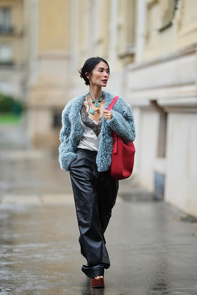 Frau trägt silbernes Camisole mit schwarzer Spitze, weite Lederhose und flauschige Faux-Fur-Jacke in Eisblau