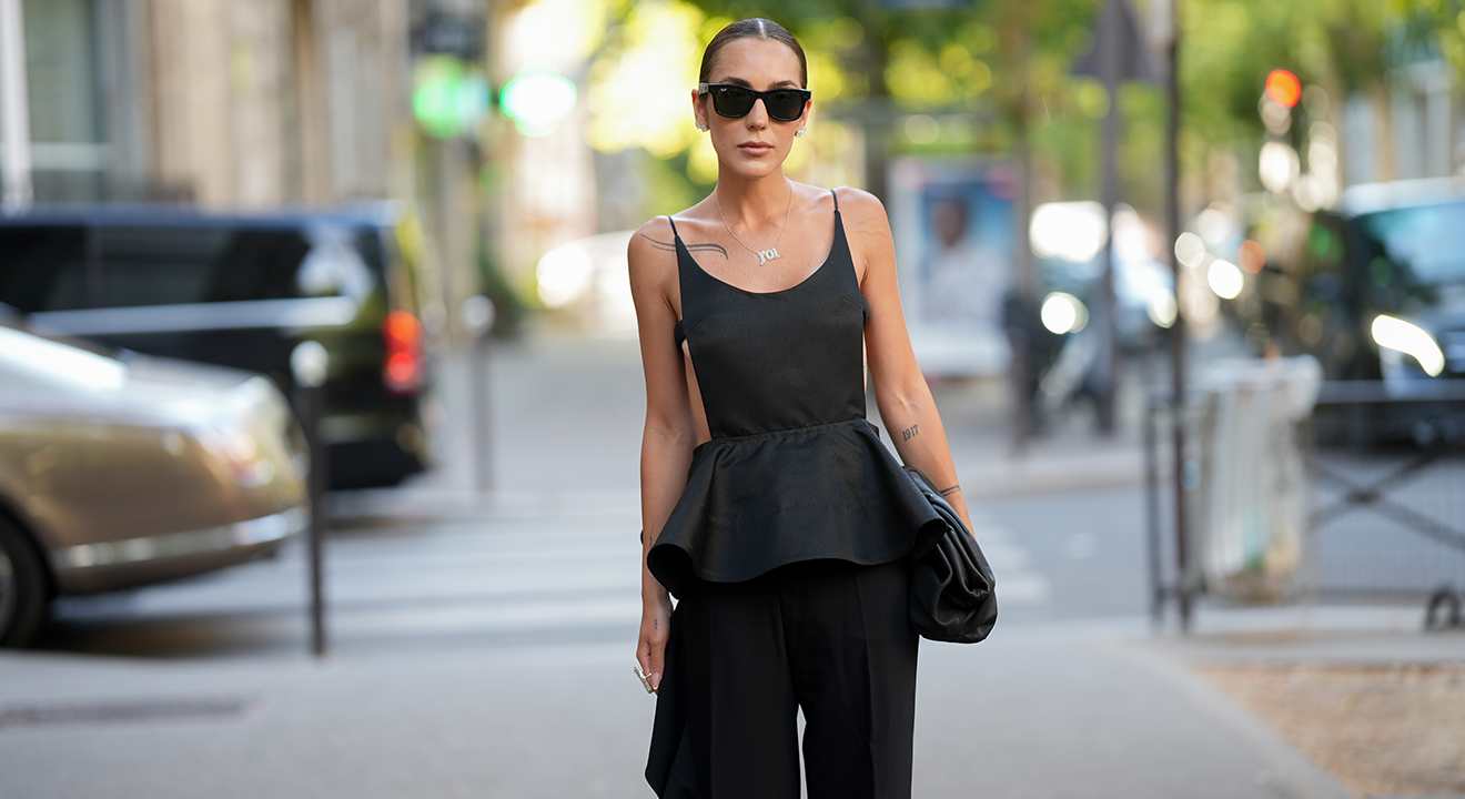 Frau trägt schwarzes Peplum, kombiniert mit passender Sonnenbrille und Handtasche,
