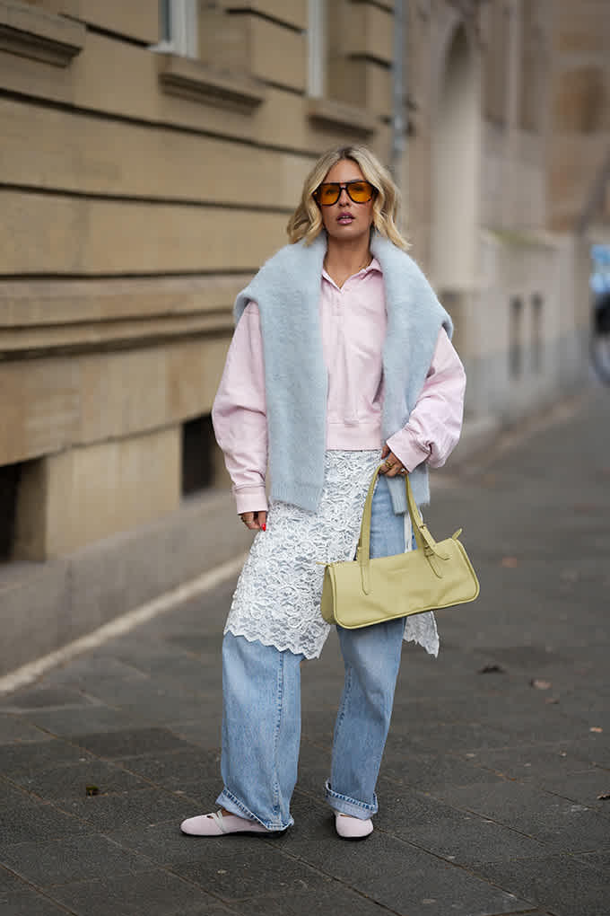 Layering-Look mit rosa Sweatshirt, hellblauem Pullover als Schulterschal und weiten Jeans
