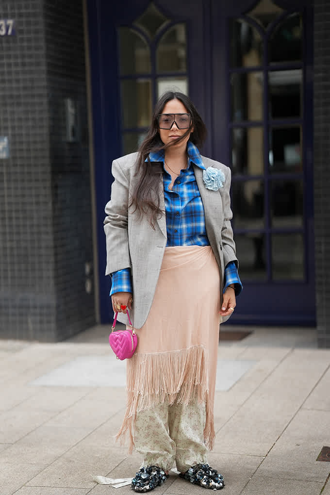 Streetstyle-Look mit grauem Blazer, blau-kariertem Hemd, Fransenrock und pinker Herztasche