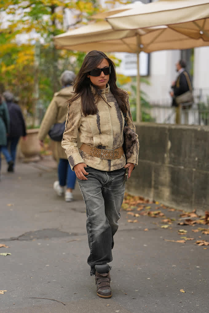 Frau mit braunen Wedge-Sneakern, weiter Jeans und einer beigen Jacke beim Spaziergang durch die Stadt