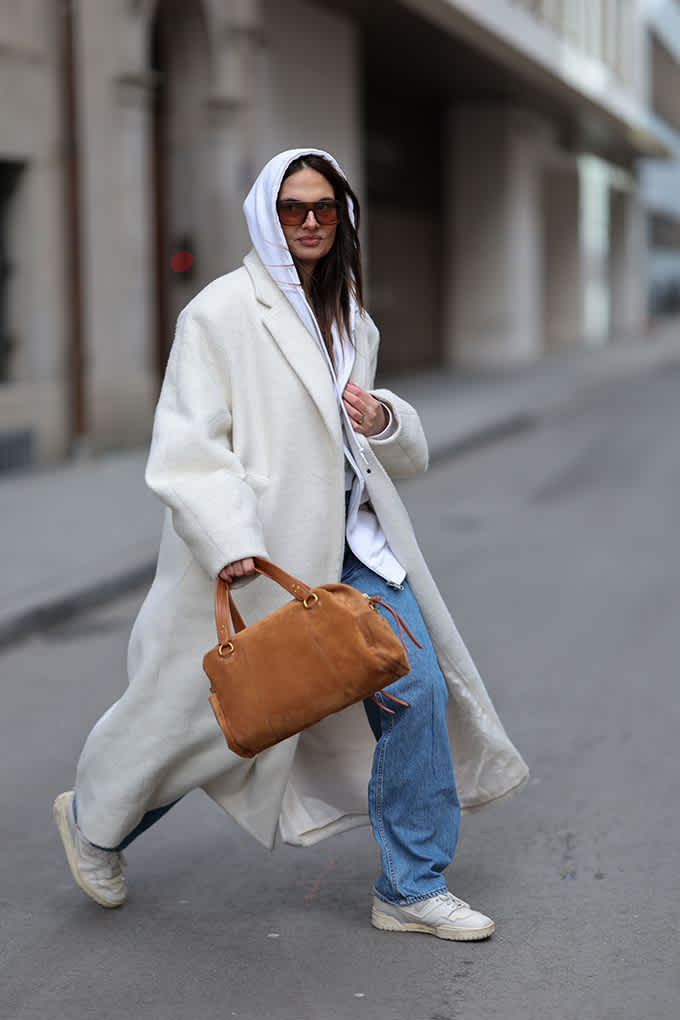 Streetstyle-Look mit langem Wollmantel, Hoodie und cognacfarbener Wildledertasche