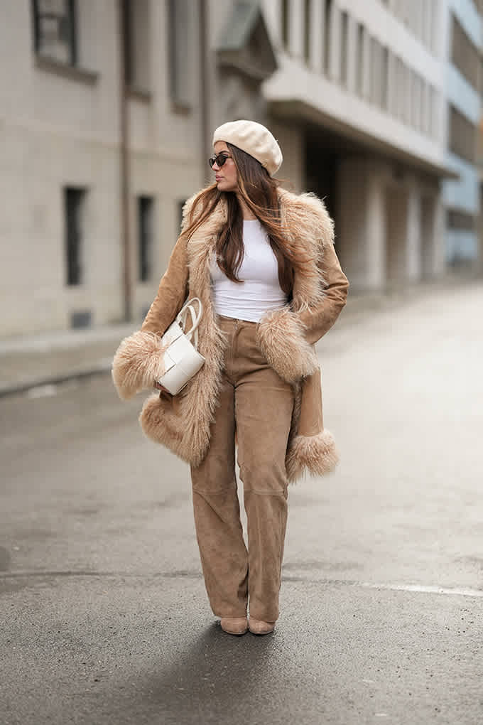 Beiger Boho Chic-Winterlook mit Fellmantel, Wildlederhose, Baskenmütze und weißer Tasche