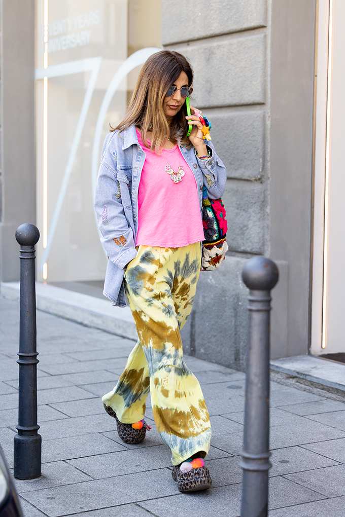 Frau trägt ganz buntes Outfit mit gelber Tie Dye Hose und pinkem Shirt 