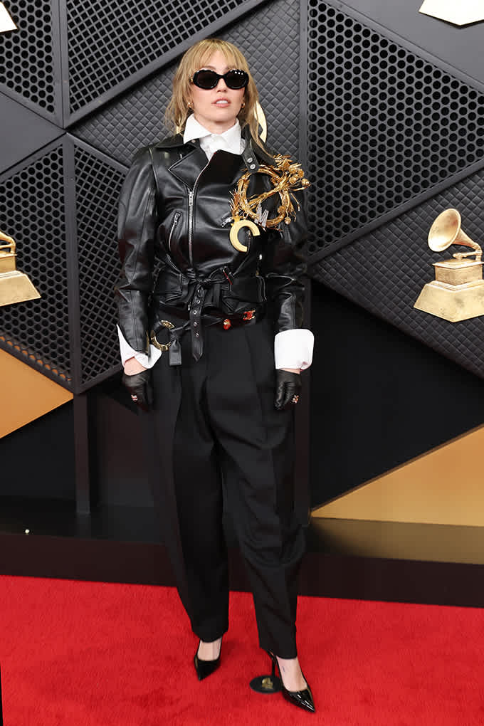 Miley Cyrus auf dem Grammy-Teppich in schwarzer Bikerjacke, weißem Hemd und Anzughose mit spitzen Lackpumps