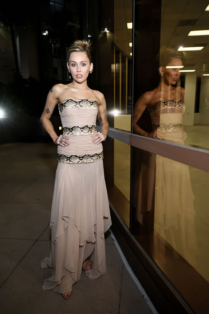 Miley Cyrus im schulterfreien Chiffonkleid in Nude mit Schlangenmuster-Details und Sandaletten