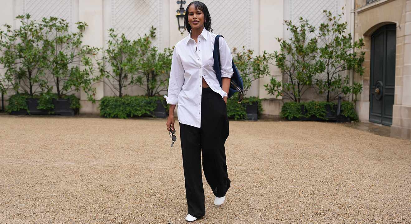 Frau in weißer Oversize-Bluse und schwarzer Wide-Leg-Hose trägt weiße Pumps im Streetstyle-Look