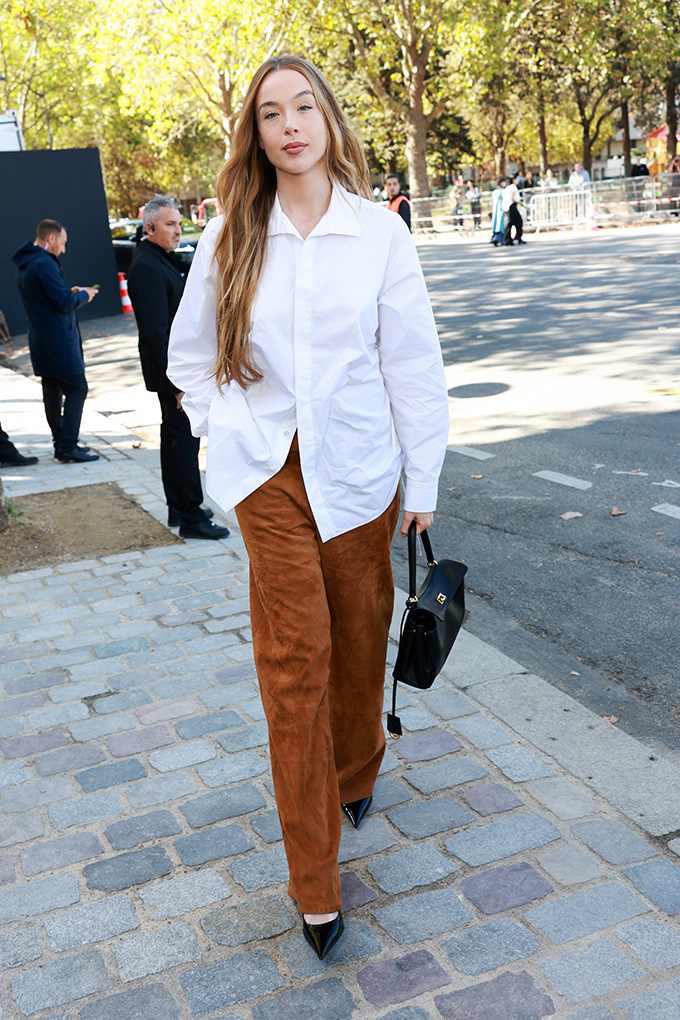 Frau in weißer Oversize-Bluse und cognacfarbener Wildlederhose trägt spitze schwarze Lackpumps