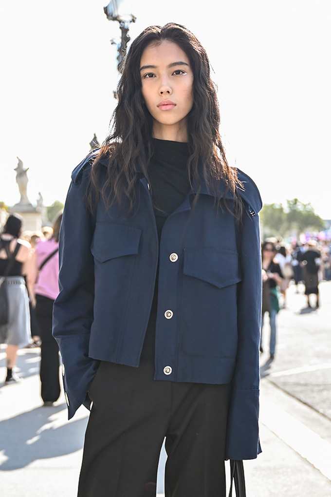 Frau in navyblauer Fieldjacket mit Brusttaschen über schwarzem Shirt und weiter Hose im Soft Tailoring-Style
