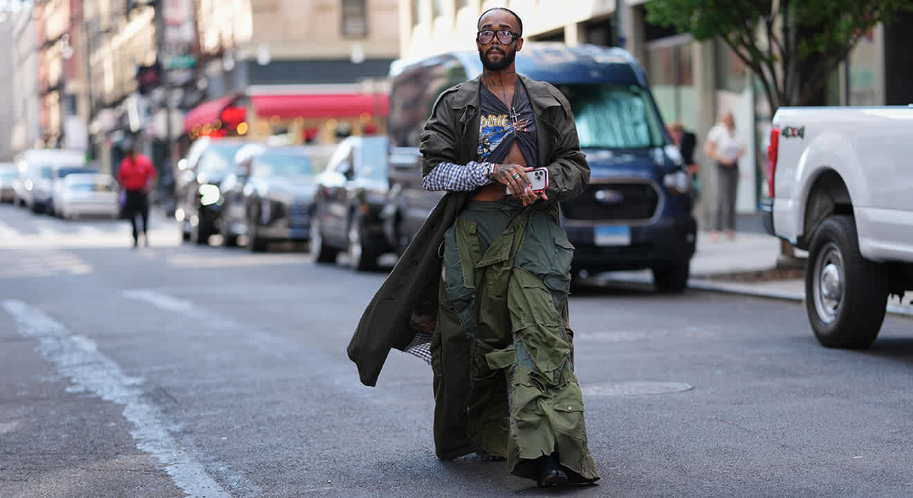 Mann im Layering-Look mit olivgrünem Mantel und destroyed Cargohose im Techwear-Style