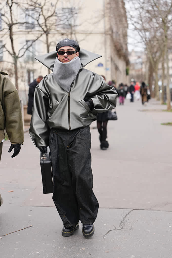Mann in Lederjacke mit XL-Kragen und weiter Baggy-Jeans trägt schwarze Boots mit Profilsohle