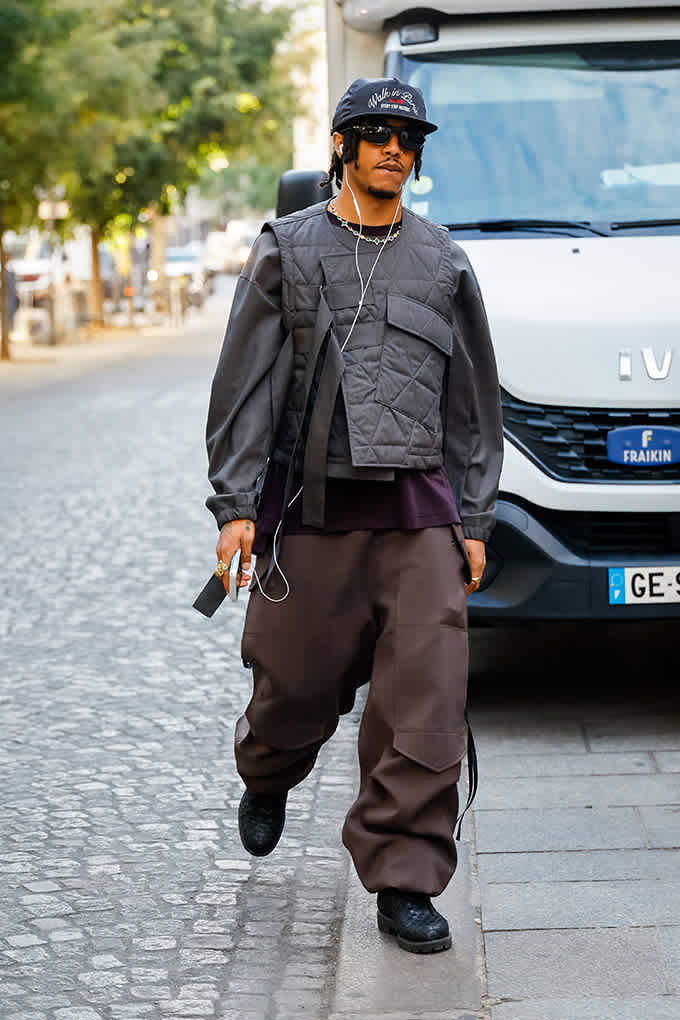 Mann in Steppweste über Jacke und brauner Baggy-Cargohose trägt schwarze Boots mit Profilsohle