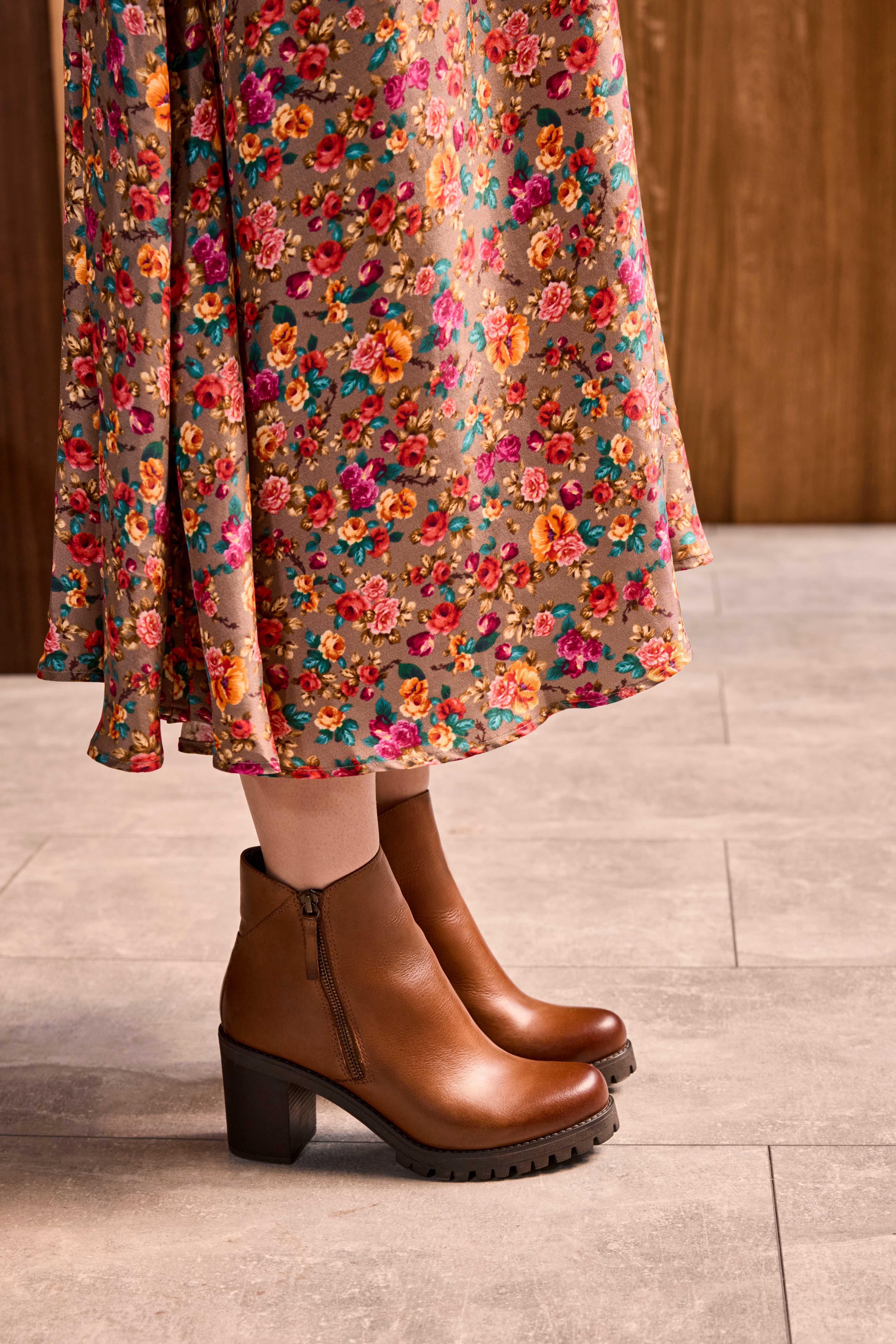 Frau in braunen Ankle Boots, trägt beiges Blumenkleid