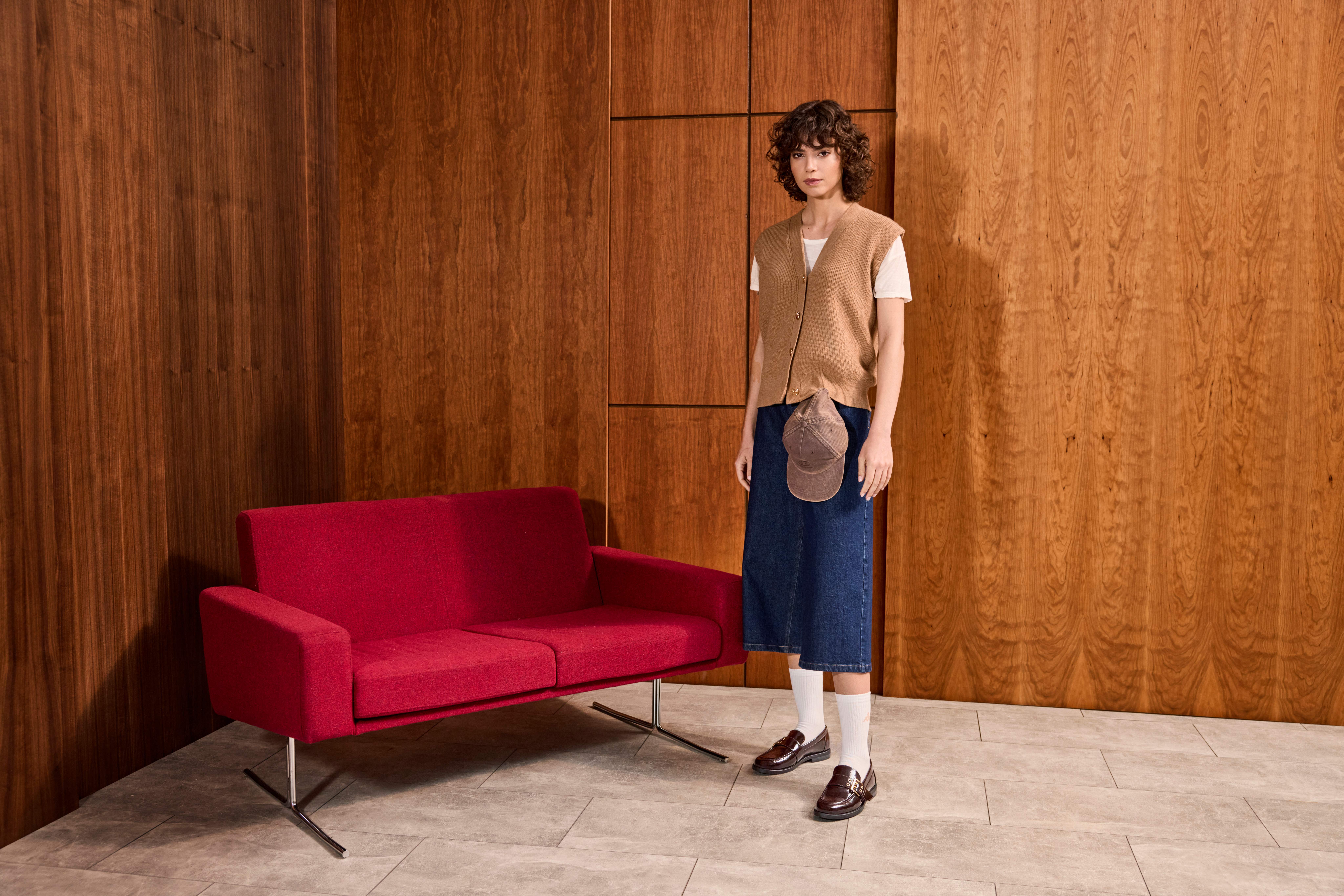 Una donna indossa ancora una volta una maglietta bianca con un gilet di maglia beige, jeans culotte blu scuro e mocassini marroni