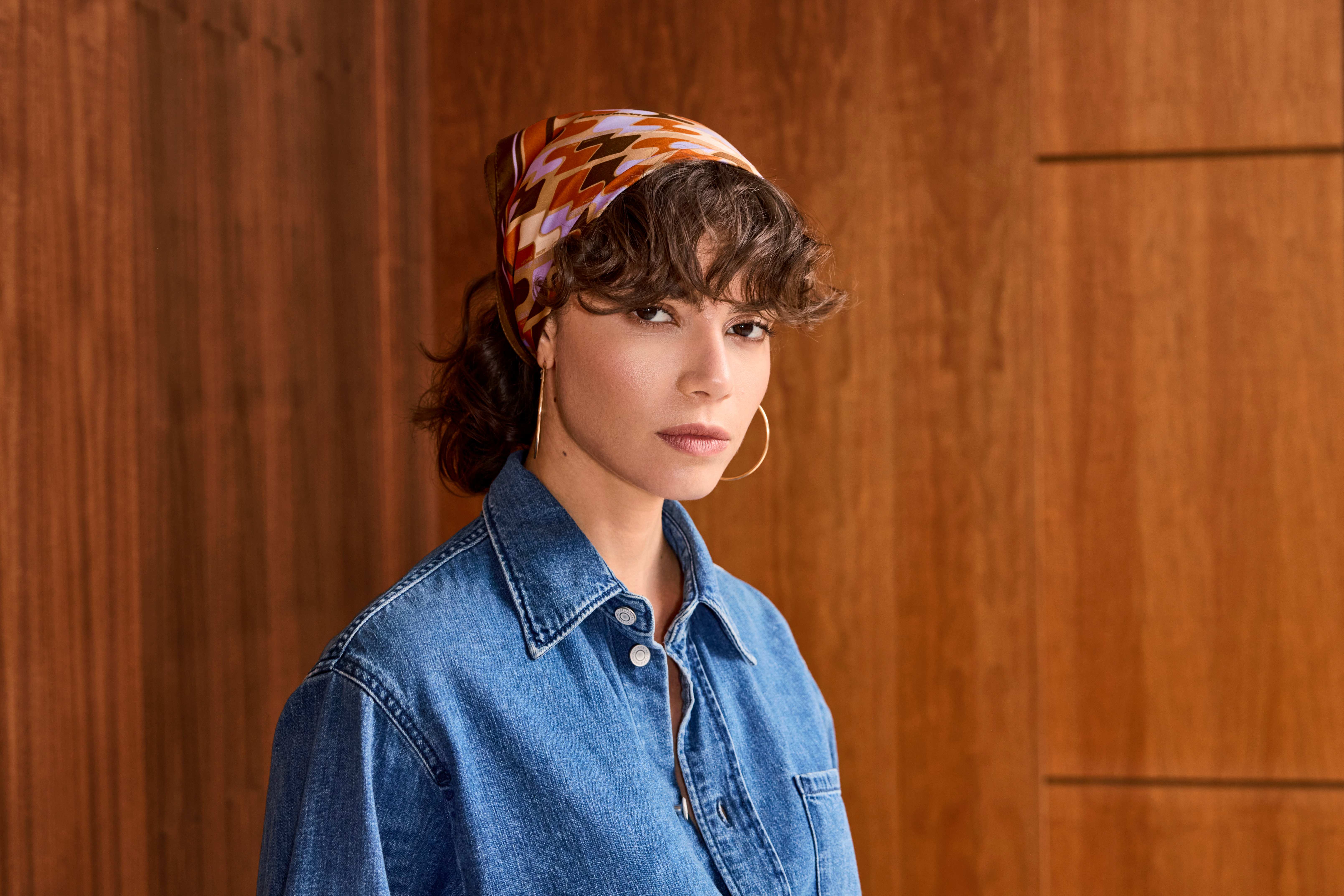 Donna bruna con salopette di jeans e foulard a fantasia