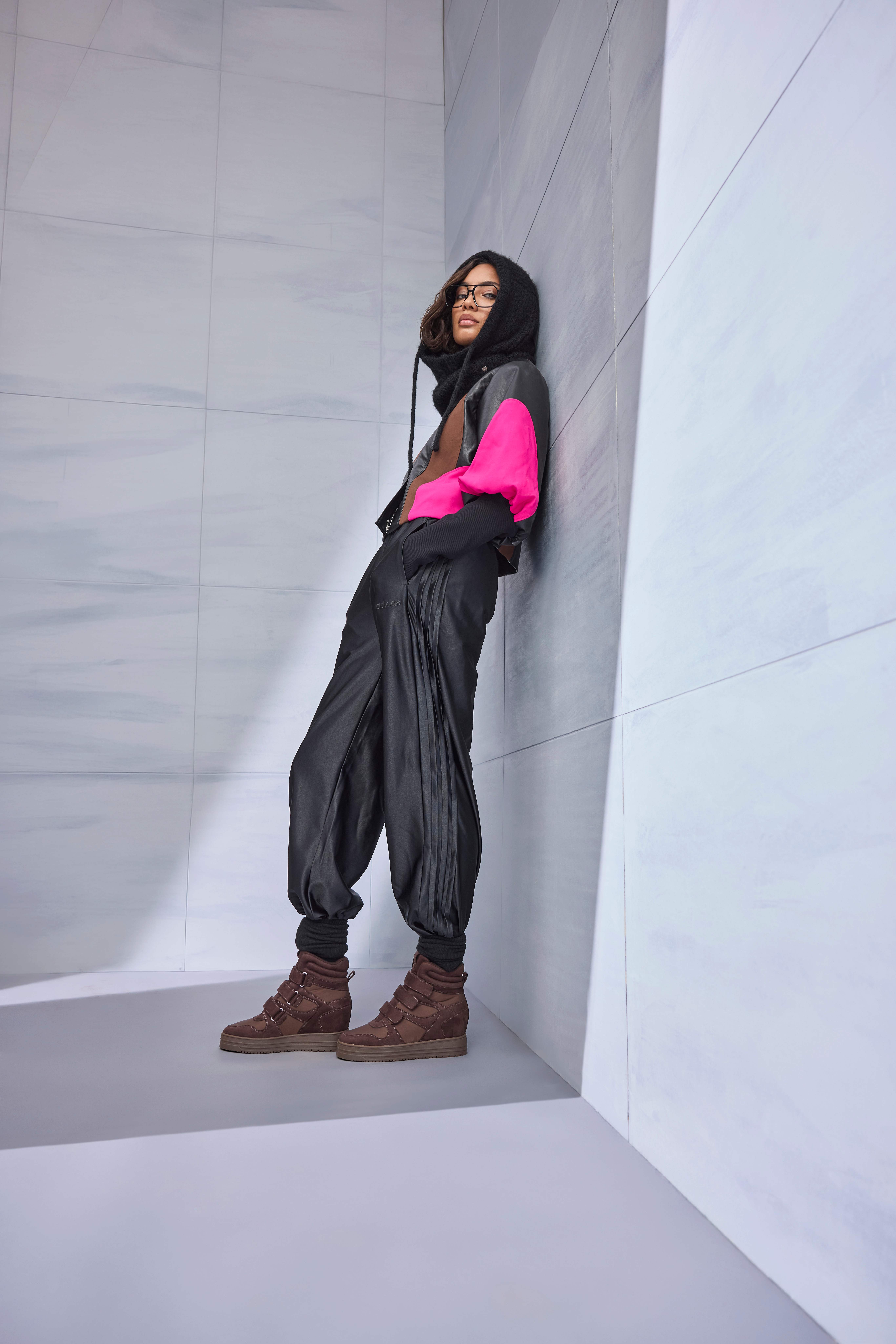 Frau trägt sportliche Jacke mit Kapuze, dazu schwarze Hose und braune Sneaker-Wedges