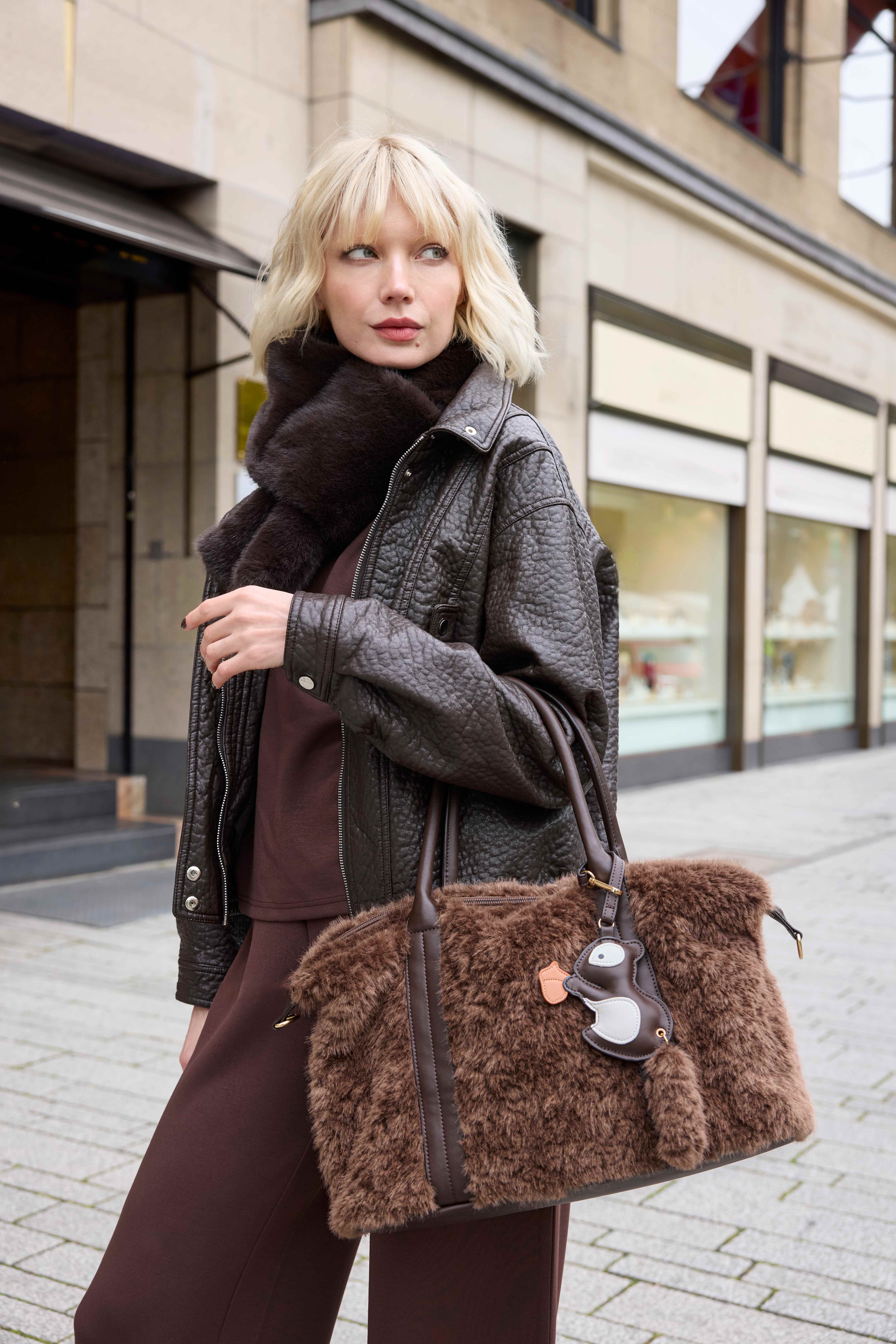 Brauner Winterlook mit Lederjacke, Fellschal und großer Plüschtasche mit Anhänger